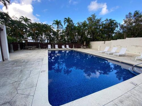 a swimming pool with white chairs and a blue at Oceanview Condo with Loft & AC in Kaaawa
