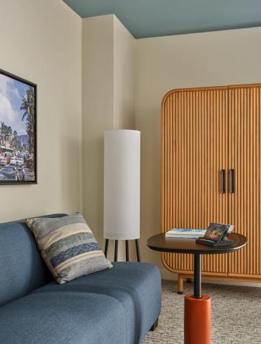 a bedroom with a blue couch and a table at Romer House Waikiki in Honolulu