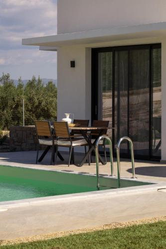 a house with a pool and a table next to a house at Flamingo Living Halkidiki - The Villas in Áyios Mámas