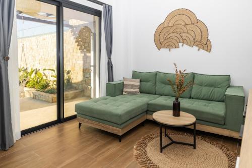 a living room with a green couch and a table at Flamingo Living Halkidiki - The Villas in Áyios Mámas