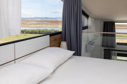 a bedroom with a bed and a large window at Flamingo Living Halkidiki - The Villas in Áyios Mámas