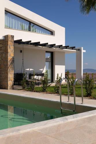 a house with a swimming pool in front of it at Flamingo Living Halkidiki - The Villas in Áyios Mámas