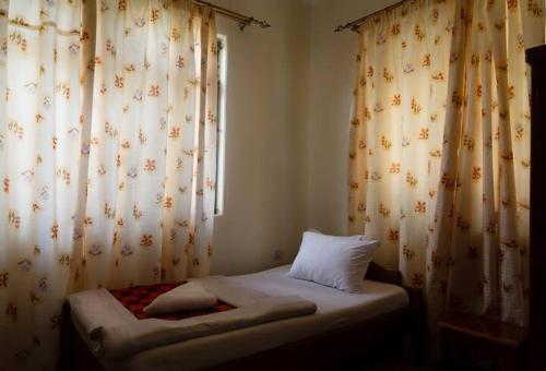 a small bed in a room with curtains and a window at Marangu Serenity Homes in Marangu