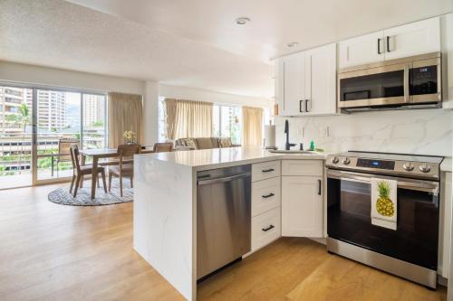a kitchen with white cabinets and a table with chairs at City and Palm View Oceanfront Bliss with Free Parking in Honolulu
