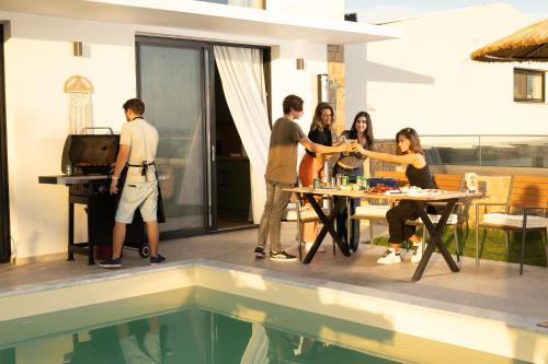 a group of people standing around a table by a pool at Flamingo Living Halkidiki - The Villas in Áyios Mámas