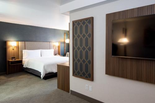 a hotel room with a bed and a flat screen tv at Holiday Inn Hinton by IHG in Hinton