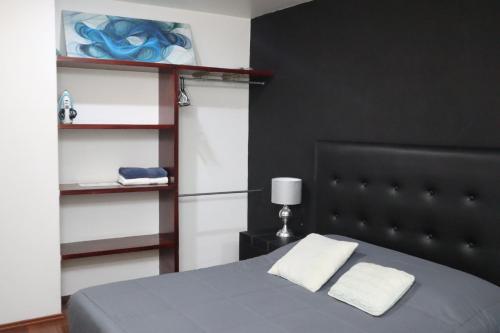 a bedroom with a bed with a black headboard and shelves at Super Suite con baño y cocina excelente ubicación in Mexico City