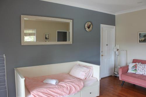 a room with a bed with a mirror and a chair at Bryn Glas Farm Stay in Moruya