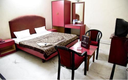 a bedroom with a bed and a table and chairs at Hotel Mayur in Gwalior