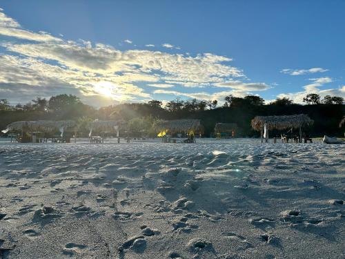 a beach with tables and huts on the sand at A Piece of Paradise in San Carlos