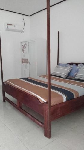 a bed with a wooden frame in a room at Losmen katiet beach front, lances right surf camp peter Homestay in Katiet