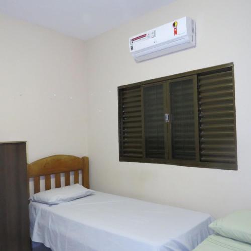 a bedroom with two beds and a window with a air conditioner at Hostel ElianeMS Quartos Privativos com Banheiro in Campo Grande