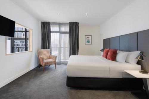 a hotel room with a large bed and a chair at Adina Citylife Auckland in Auckland