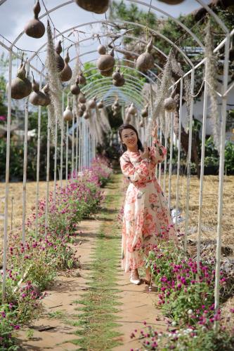 a woman walking down a path in a garden at Upes Garden Homestay Bien Ho in Bien Ho