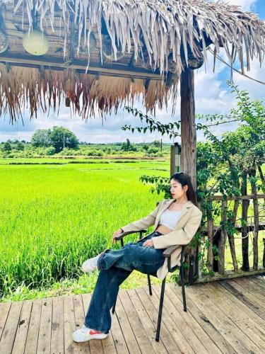 a woman sitting in a chair under an umbrella at Upes Garden Homestay Bien Ho in Bien Ho