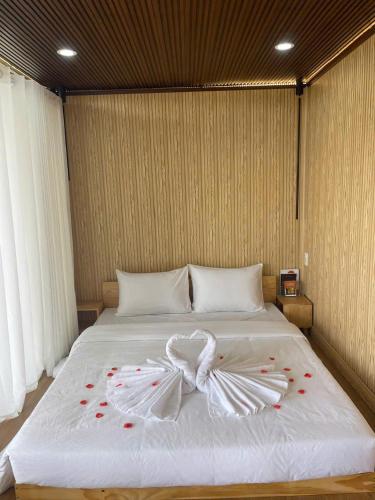 a large white bed with red rose petals on it at Upes Garden Homestay Bien Ho in Bien Ho