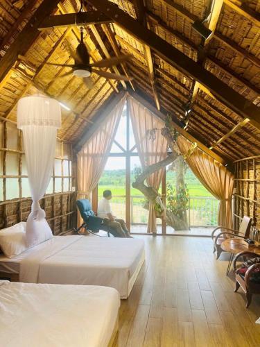 a man sitting in a chair in a room with two beds at Upes Garden Homestay Bien Ho in Bien Ho