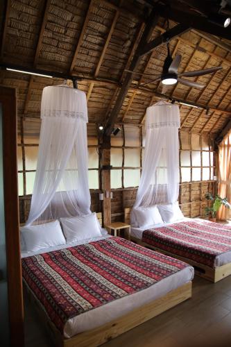 a bedroom with two beds in a straw hut at Upes Garden Homestay Bien Ho in Bien Ho