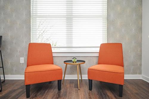 zwei orangefarbene Stühle und ein Tisch vor einem Fenster in der Unterkunft Luxury New Penthouse Roof Balcony Washer Dryer B406 in Atlanta