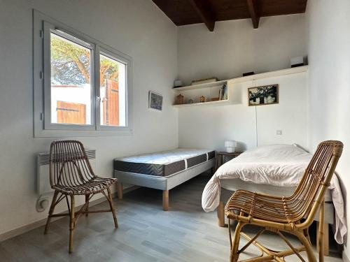 une chambre avec un lit et deux chaises et une fenêtre dans l'établissement Villa 3 chambres à La Palmyre avec terrasse, parking et WiFi - FR-1-705-98, aux Mathes