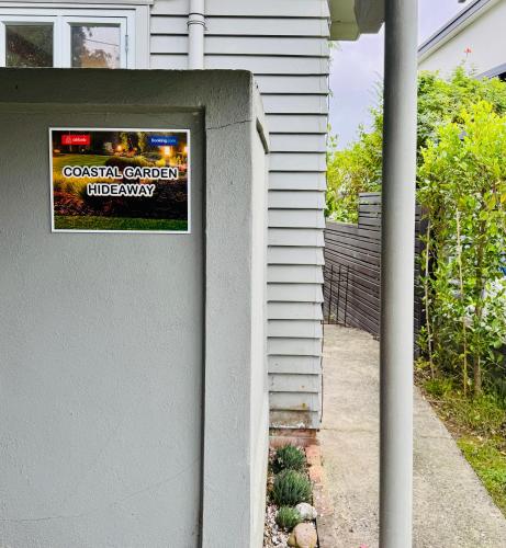 a sign on a wall next to a house at Coastal Garden Family Hideaway in Auckland
