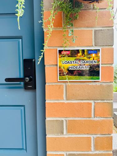a sign on a brick wall next to a door at Coastal Garden Family Hideaway in Auckland