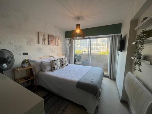 Un dormitorio con una cama y una ventana grande. en Lindo departamento tipo Loft en Ñuñoa, en Santiago
