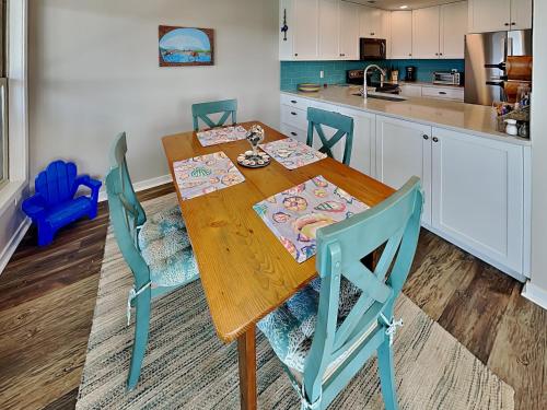 a kitchen with a wooden table and blue chairs at Slow Motion #8A in Topsail Beach