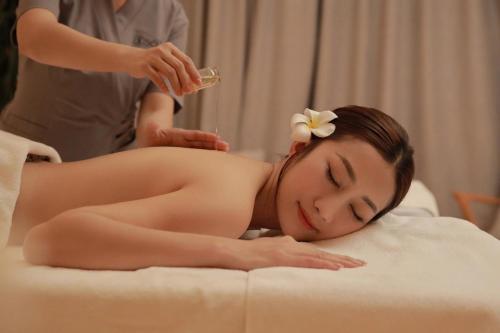 a woman laying on a bed getting a massage at The Empyrean Cam Ranh Beach Resort in Cam Ranh