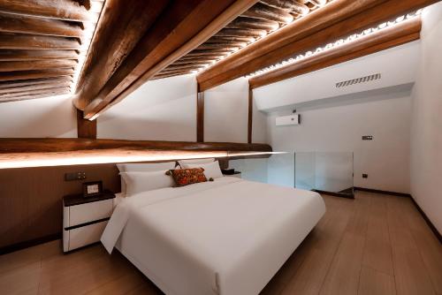 a bedroom with a white bed and a wooden ceiling at Lishè Hotel in Pingyao