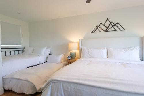two beds in a bedroom with white sheets and pillows at Skyview in Fraser