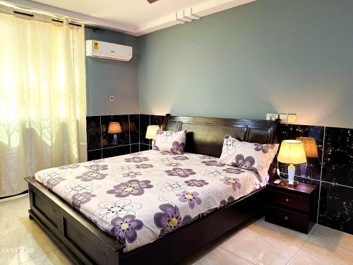 a bedroom with a bed with purple flowers on it at Lexsarp Apartments in Tema