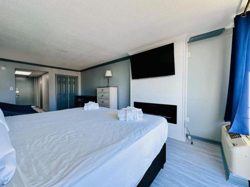 a bedroom with a large white bed with a flat screen tv at Lovely Beach View Condo,King,Pool,M11 in Myrtle Beach