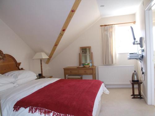 a bedroom with a bed with a red blanket on it at Chilgrove Farm Bed & Breakfast in Chilgrove