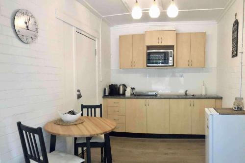 a kitchen with a table and a clock on the wall at Annies Barn, Fitzroy Falls in Fitzroy Falls