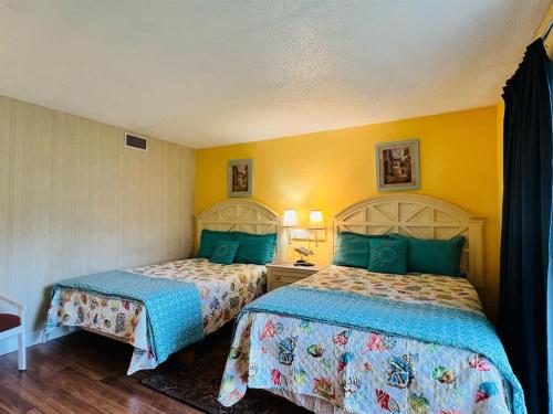 two beds in a room with yellow walls at *A FAMILY GETAWAY*Pool*Steps to the Beach*Approved Dogs*D18 in Myrtle Beach