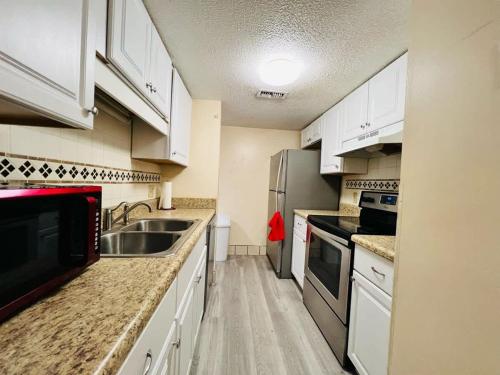 a small kitchen with white cabinets and a sink at *A FAMILY GETAWAY*Pool*Steps to the Beach*Approved Dogs*D18 in Myrtle Beach