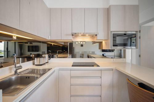 a kitchen with white cabinets and a sink and a microwave at Cassia Residences in Laguna by Banyan Living in Laguna Phuket