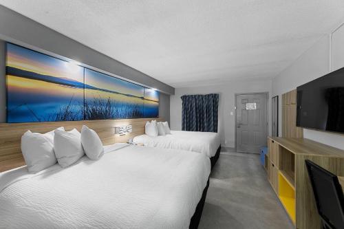 a hotel room with two beds and a flat screen tv at Days Inn by Wyndham San Antonio Near Lackland AFB in San Antonio