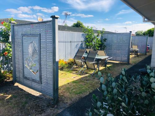 a garden with a gate and a table and chairs at Blue Haven Motel in Mount Maunganui
