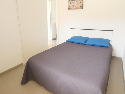 une chambre avec un lit avec des oreillers bleus dessus dans l'établissement Appartement F2 avec terrasse, jardin, parking et accès piscine à 500m du village d'Argelès-sur-Mer - FR-1-732-63, à Argelès-sur-Mer