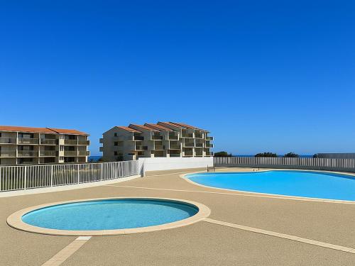 deux piscines dans un parking avec des bâtiments en arrière-plan dans l'établissement Studio moderne avec piscine, proche plage et commodités, Saint-Cyprien - FR-1-732-71, à Saint-Cyprien