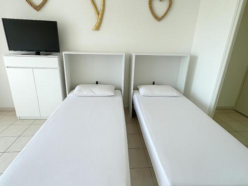 Cette chambre comprend 2 lits blancs et une télévision. dans l'établissement Studio moderne avec piscine, proche plage et commodités, Saint-Cyprien - FR-1-732-71, à Saint-Cyprien
