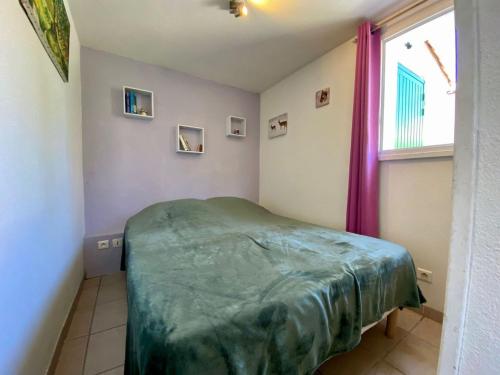 - une chambre avec un lit vert dans une pièce dotée d'une fenêtre dans l'établissement Maison de vacances avec piscine et parking à Loupian - FR-1-604-55, à Loupian