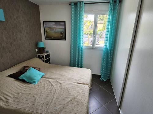 - une chambre avec un lit doté d'un oreiller bleu et d'une fenêtre dans l'établissement Appartement 3 chambres proche mer, terrasse sud - FR-1-768-120, à La Garonnette-Plage