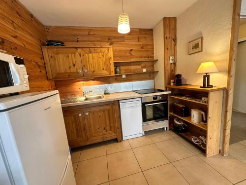 une cuisine avec des armoires en bois et un réfrigérateur blanc dans l'établissement Appartement calme avec balcon et vue montagne pour 4 pers - FR-1-515-227, à Villard-de-Lans