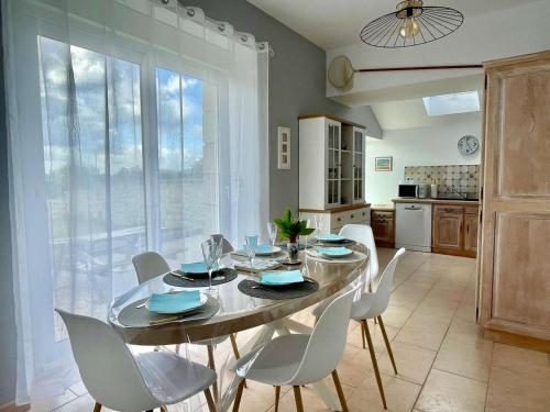 une salle à manger avec une table et des chaises blanches dans l'établissement Maison 3 étoiles rénovée 2025, terrasse, accueil animaux, bord de mer - FR-1-542-71, à Pleumeur-Bodou