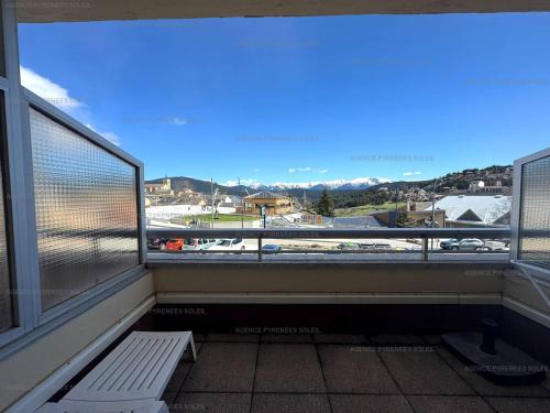un balcon avec un banc et une vue sur une ville dans l'établissement Studio cabine 4 pers au cœur de la station, terrasse Sud - FR-1-295-207, aux Angles