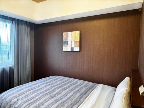 a bedroom with a bed and a painting on the wall at Hotel Route-Inn Oyama in Oyama