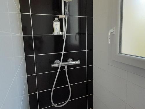 La salle de bains est pourvue d'une douche avec un tuyau et de carrelage noir. dans l'établissement Maison spacieuse à Capbreton, proche port et plages, jusqu'à 6 personnes - FR-1-239-1122, à Capbreton